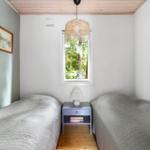 Two beds with mattresses and a nightstand with a lamp.