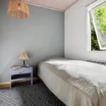 A bedroom with bed, nightstand, and window with view of greenery.