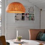 Ein Raum mit braunem Sofa, weißer Wand und runden Tisch mit Lampe.