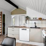 Küche mit Holz Arbeitsplatte, Spüle und Backofen unter schrägem Dach.