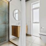 Badezimmer mit Dusche, Waschbecken und Toilette.