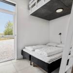Zimmer mit Doppelbett, Fenster und oberem Schlafbereich mit Leiter.