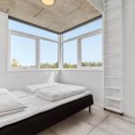 Schlafzimmer mit großem Fenster und Doppelbett.