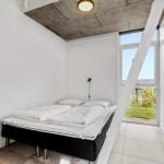 Schlafzimmer mit Bett, Fenster und Betondecke.