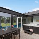 Terrasse mit Hot Tub, Esstisch und Blick auf Pool und Garten.