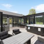 Terrasse mit Sitzgelegenheiten und Whirlpool. Glasfassade führt in das Innere.