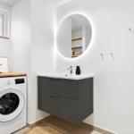 Badezimmer mit Waschmaschine, Spiegelschrank und Fenster.