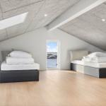 Zwei Betten in einem Dachzimmer mit Holzboden und Fensterblick.