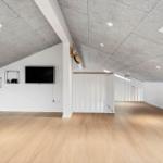 Dachgeschosszimmer mit Holzboden, Fernseher und Schränken an der Wand.