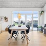 Essbereich mit Tisch und Stühlen, Wohnbereich mit Sofas und großem Fenster.