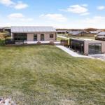 Moderne Villa mit großem Garten und Terrasse. Sonniger Tag mit klarem Himmel.
