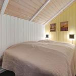 Schlafzimmer mit Bett, gelben Wänden und Holzdecke.