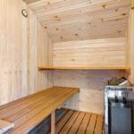 Sauna mit Holzbank, Heizung und Wanduhr.
