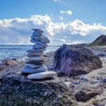 Stone cairn on the beach with view of the sea and cloudy sky.