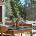 Dining table with wine bottle and glasses in front of large window with garden view.