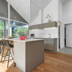 Modern kitchen with island, bar stools, and view of the garden.
