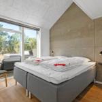 Bedroom with bed, window, and chair. Wooden floor and concrete wall.