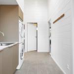 Kitchen with sink and washing machine. View into bedroom with loft bed.