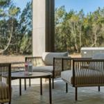 Terrace with seating group, table, and view of forest. Hot tub in background.