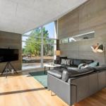 Living room with large sofa, TV, and panoramic windows to the outside.