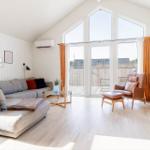 Wohnzimmer mit Sofa, Sessel und großem Fenster zur Terrasse.