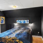 Schlafzimmer mit Bett, schwarzen Wänden und Fenster zum See.