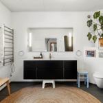 Badezimmer mit Waschbecken, Spiegel, Toilette und Pflanze.