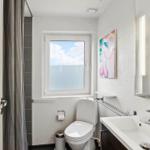 Badezimmer mit Toilette, Waschbecken und Dusche. Fenster mit Meerblick.