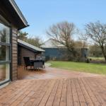 Wooden terrace with seating, view of lawn and farm building.