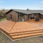 Modern villa with large wooden terrace and outdoor grill area.