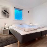 Schlafzimmer mit Bett, Nachttisch und Fenster. Holzboden und Wandbilder.