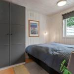 Schlafzimmer mit Bett, Kleiderschrank und Fenster mit Blick auf Außenbereich.