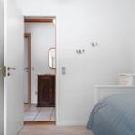 Schlafzimmer mit Bett, Kleiderhaken und Tür zum Flur.