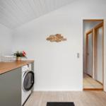 Waschmaschine mit Holzoberfläche und Fischdekoration an der Wand.