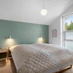 Schlafzimmer mit Bett, Nachttisch und Fenster. Wand in Grün, Holzboden und Deckenleuchte.