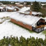 Ein Haus mit Schnee bedecktem Dach und Terrasse im Winter.