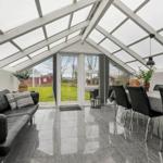 Großes Wohn- und Esszimmer mit Glasdach und Terrassentür.