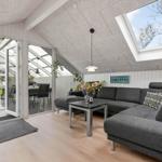 Wohnzimmer mit grauem Sofa, Tisch und Dachfenster. Durchgang zur Terrasse.
