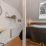 Schlafzimmer mit Dachfenster, Bett mit Holzrahmen und Wandspiegel.