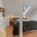 Schlafzimmer mit Dachfenster, Holzboden und Bett mit dunkler Bettwäsche.