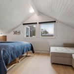 Schlafzimmer mit Bett, Sofa und zwei Fenstern an geneigtem Dach