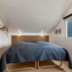 Schlafzimmer mit Bett, Fenster und Wandspiegel.