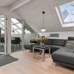 Wohnbereich mit grauem Sofa, Tisch und Fenstern zur Terrasse.