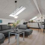 Wohnbereich mit Sofa, Esstisch und Küchenzeile unter Dachschrägen.