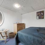 Schlafzimmer mit Bett, Schrank, runden Spiegel und Tisch.