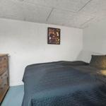 Schlafzimmer mit Bett, Holzkommode und Wandbild.