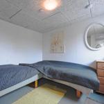 Zimmer mit zwei Betten, Holzkommode und runden Spiegel an der Wand.