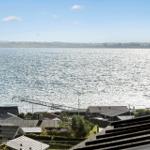 Panoramic view of the sea with a pier and houses in the foreground.