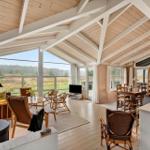 Großes Wohn- und Esszimmer mit Holzdecke und Blick auf Landschaft.