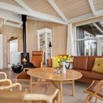 Wohnzimmer mit Holzwand, Sofa, Kamin und großem Fenster.
